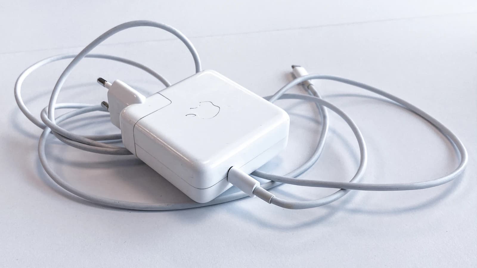 Cargador de pared con su cable enrollado sobre una superficie clara