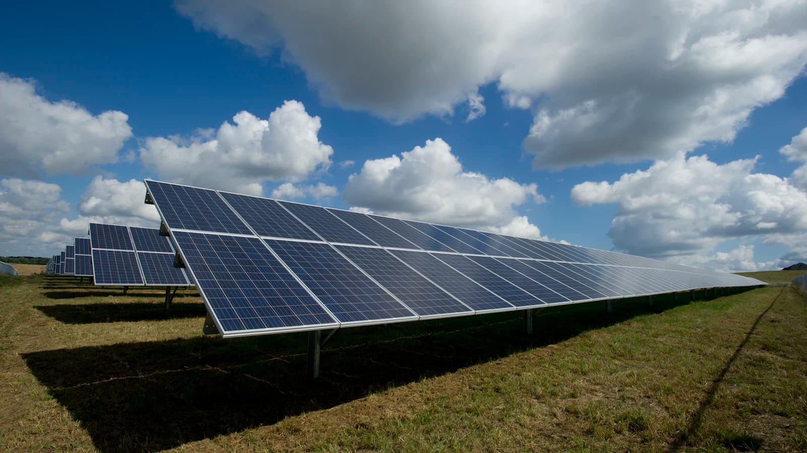 Campo de paneles solares bajo un cielo con nubes