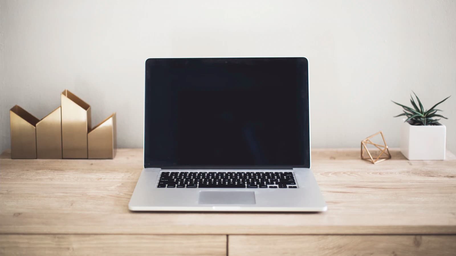 Laptop abierta sobre un escritorio de madera ordenado y luminoso