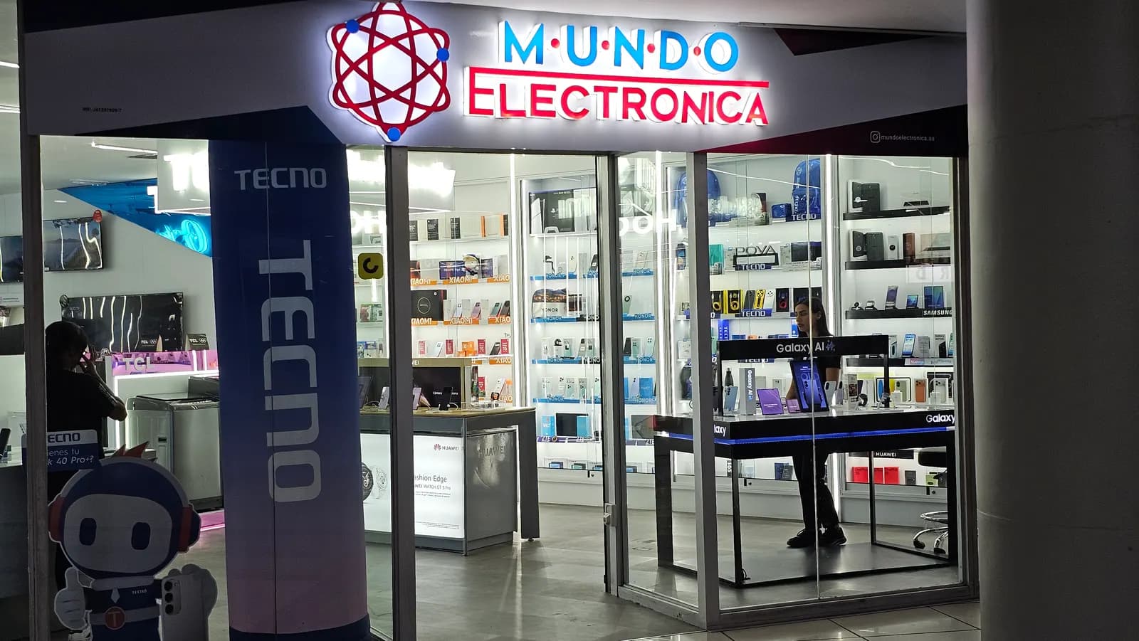 Entrada del local de El Recreo con el tótem de Tecno y la mascota recibiendo a los clientes