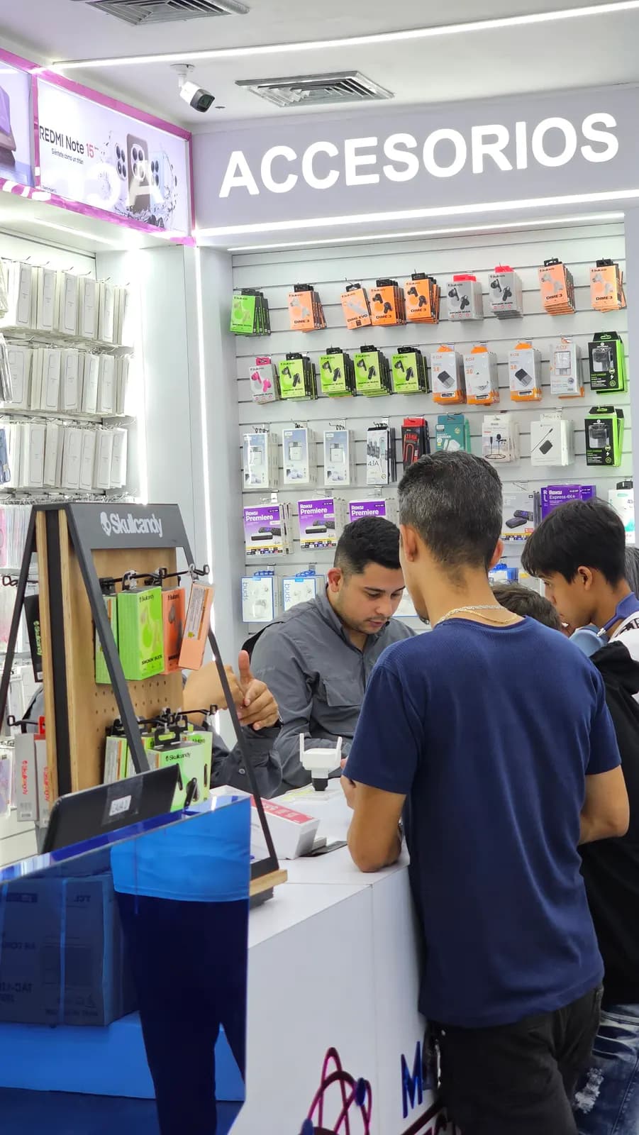 Asesores de Mundo Electrónica atendiendo a dos clientes en el área de accesorios